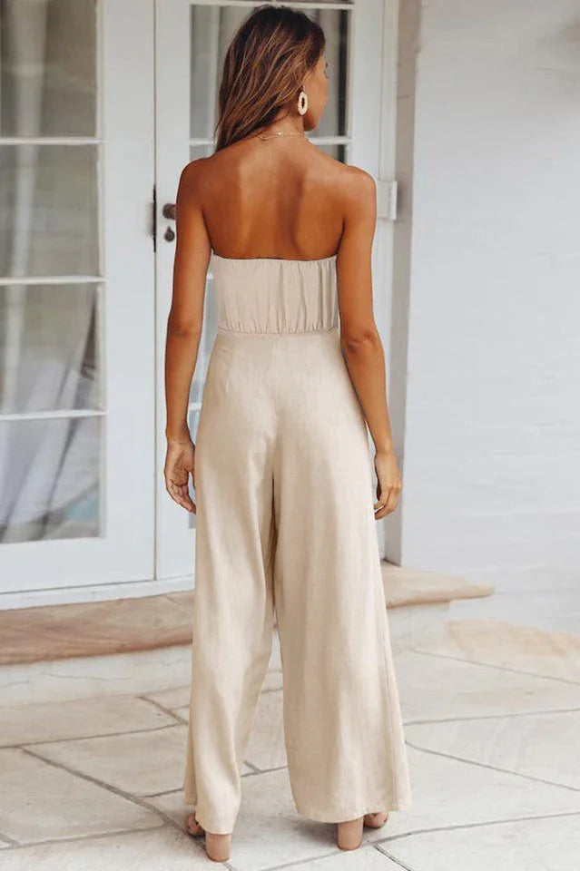 woman wearing a beige strapless jumpsuit with wide-leg pants and a tie-waist detail, back view