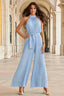 Woman standing in a light blue pleated halter neck wide leg jumpsuit.