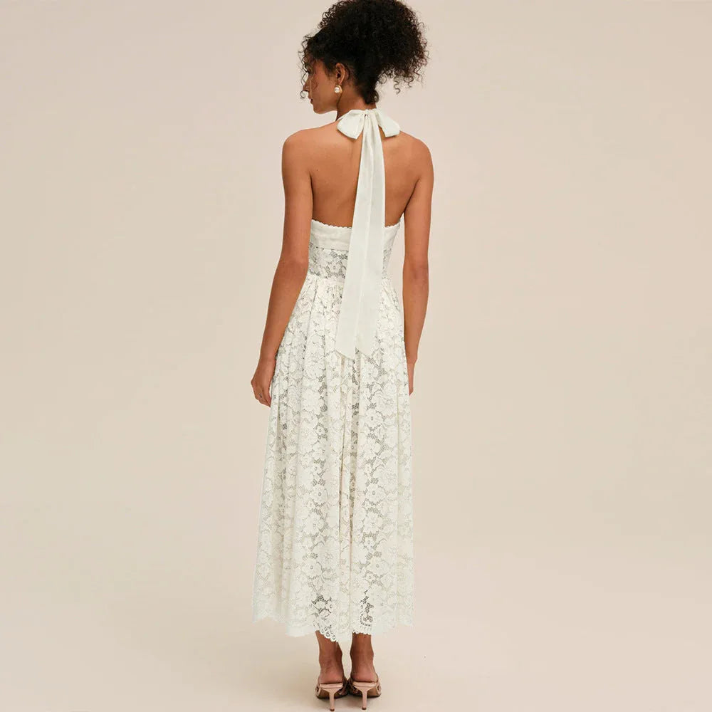 Back view of a white lace halter midi dress with a bow detail
