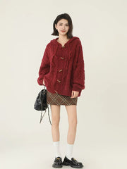 Full body shot of a woman in a burgundy cable knit hooded cardigan and plaid mini skirt.