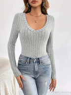 Front view of a woman wearing a grey ribbed long-sleeve V-neck top with jeans