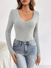 Front view of a woman wearing a grey ribbed long-sleeve V-neck top with jeans