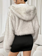 Back view of a woman wearing a white faux fur cropped hooded jacket and black dress.