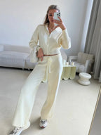 Woman posing with a cream handbag in a cream knit loungewear set