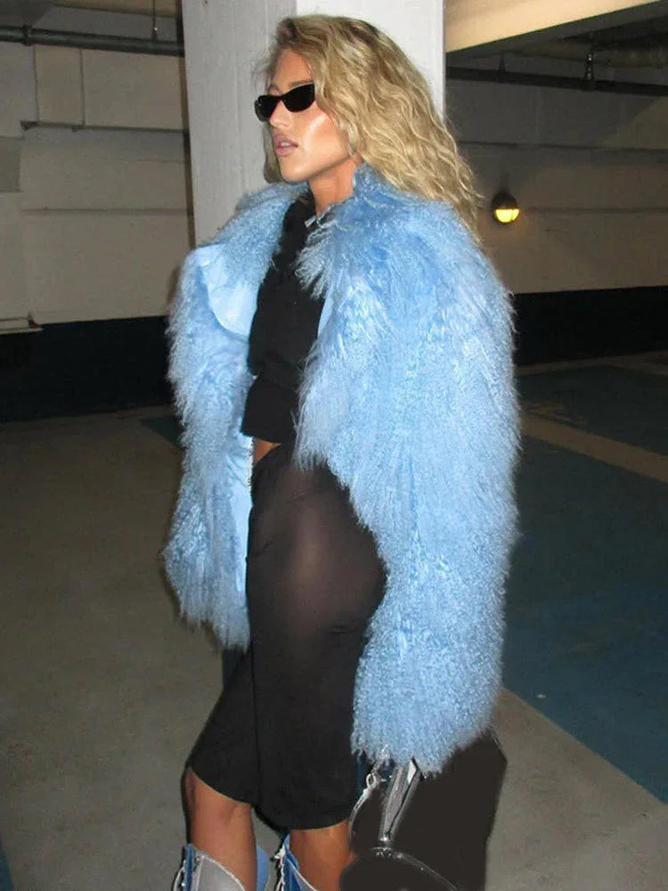 Woman wearing a light blue fluffy faux fur jacket over a black crop top and black shorts, with blue and silver lace-up boots. Main image