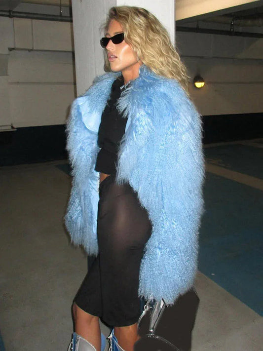 Woman wearing a light blue fluffy faux fur jacket over a black crop top and black shorts, with blue and silver lace-up boots.