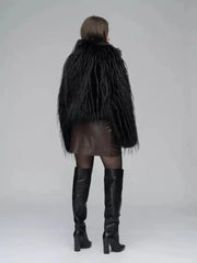 Back view of a woman in a black faux fur jacket, brown wrap dress, sheer black tights, and black knee-high boots.