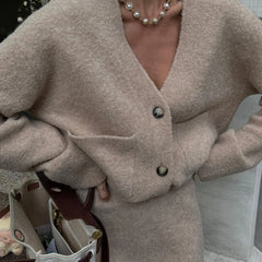 Close-up of a beige knit cardigan with buttons and pockets.