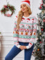 Woman wearing a pink Christmas sweater with Santa, reindeer, and candy cane print, standing in front of a Christmas tree