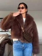 woman wearing a brown faux fur jacket with sunglasses and jeans, posing indoors