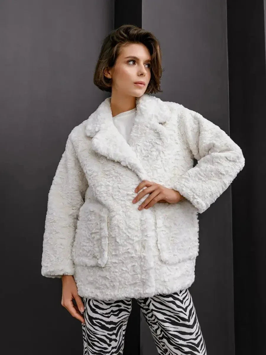 Model wearing a white textured faux fur jacket with lapel collar and button closure, paired with zebra print pants.