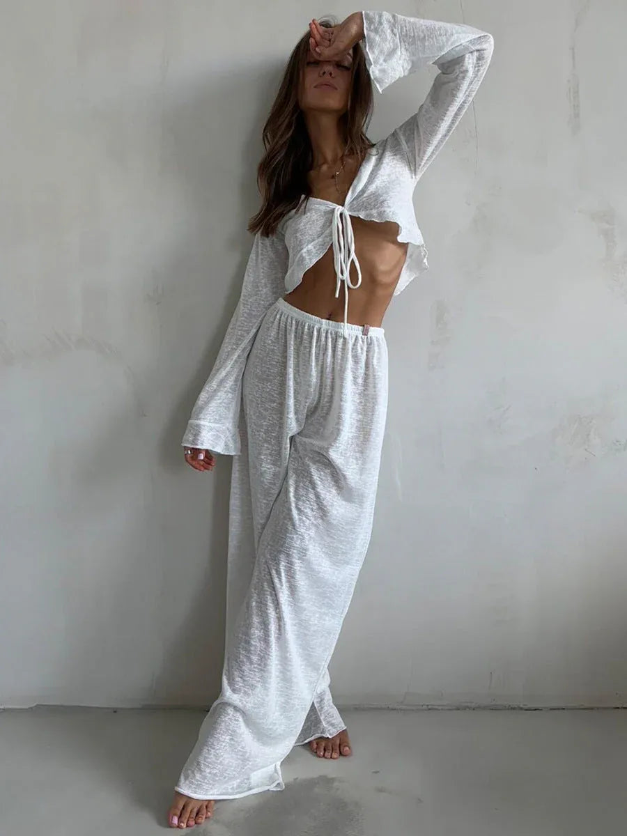 Woman in a white sheer knit outfit, adjusting her arm.