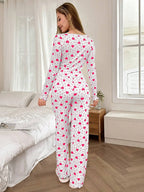 Rear view of a woman wearing a white long-sleeved pajama top and pants with a pink heart print.