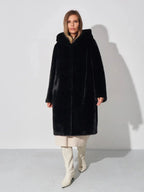 Woman wearing a black hooded faux fur coat, cream dress, and white boots, front view.