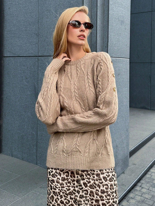 Woman wearing a tan cable knit sweater and a leopard print maxi skirt, standing outdoors.