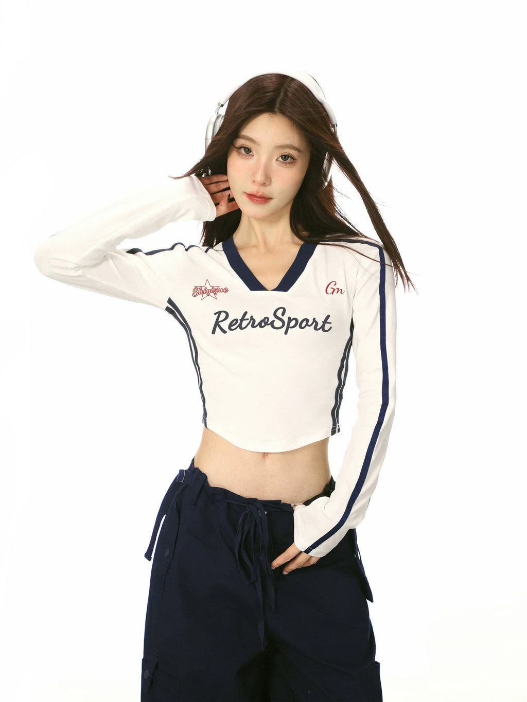 Close-up of a woman wearing a white cropped long-sleeve shirt with athletic details and navy trim.