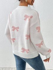 Back view of a woman wearing a white crew neck sweater with pink bow print and blue jeans
