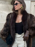 close-up of a woman wearing a luxurious brown fur coat and statement earrings