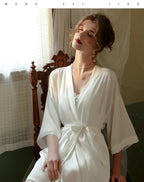 Woman wearing a white satin robe tied at the waist.