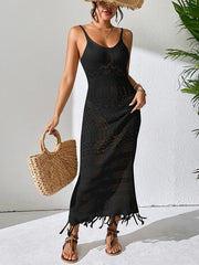 Woman wearing a black crochet maxi dress, straw hat, and straw bag