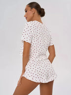 Woman wearing a white cropped t-shirt and shorts with a red heart print, viewed from the back.