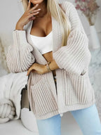 Woman posing in a beige knit cardigan and jeans