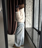 Full body mirror selfie of a woman in a cream faux fur cropped jacket and light wash wide-leg jeans.