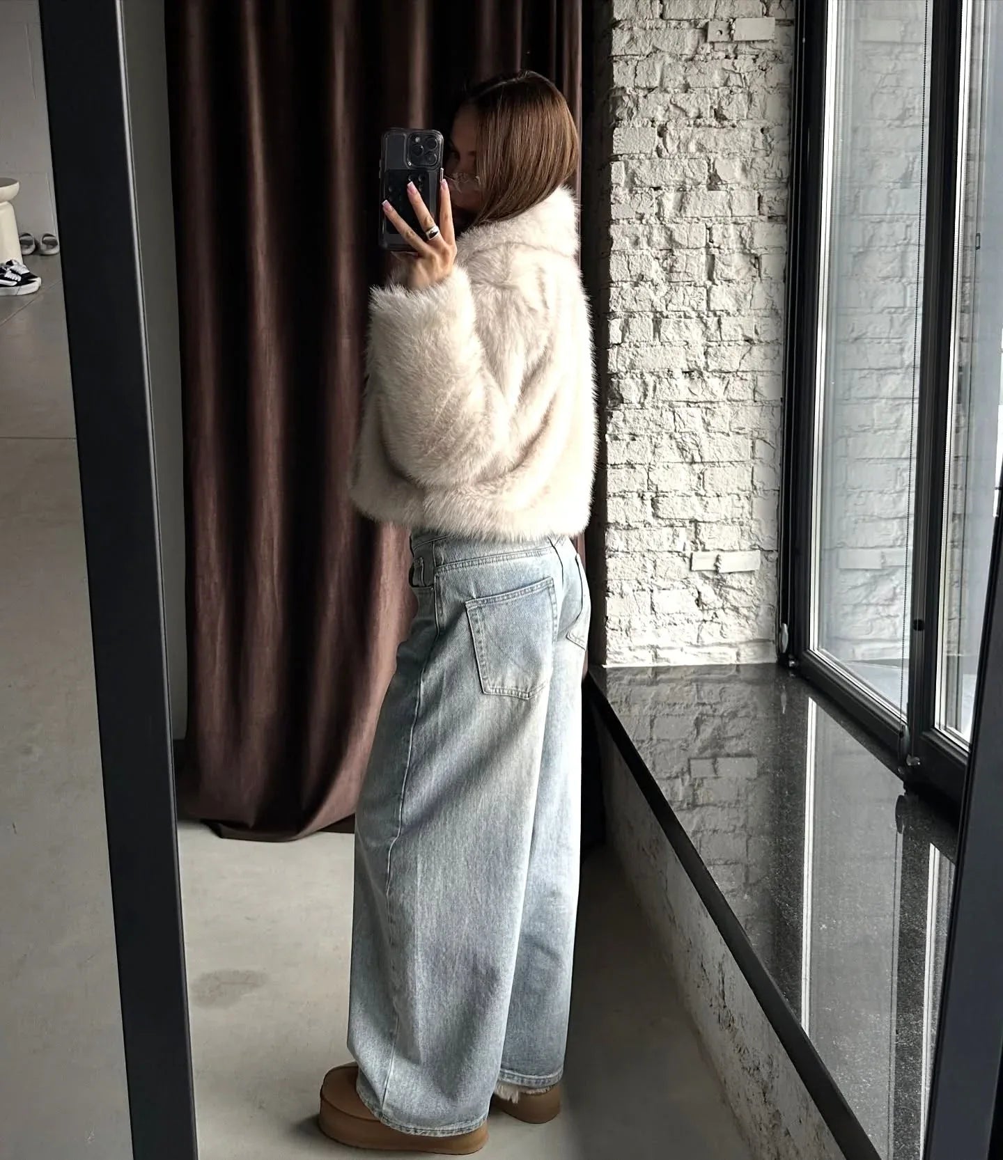 Full body mirror selfie of a woman in a cream faux fur cropped jacket and light wash wide-leg jeans.
