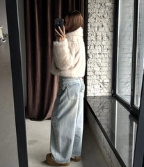 Full body mirror selfie of a woman in a cream faux fur cropped jacket and light wash wide-leg jeans.