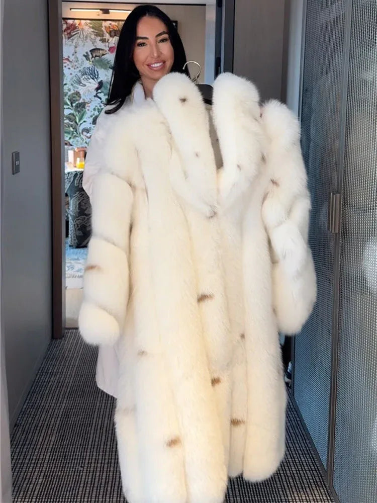 Woman holding a long white faux fur coat on a hanger, smiling.