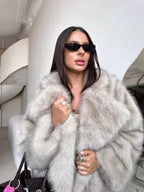 close-up of a woman wearing a light grey faux fur coat and rings