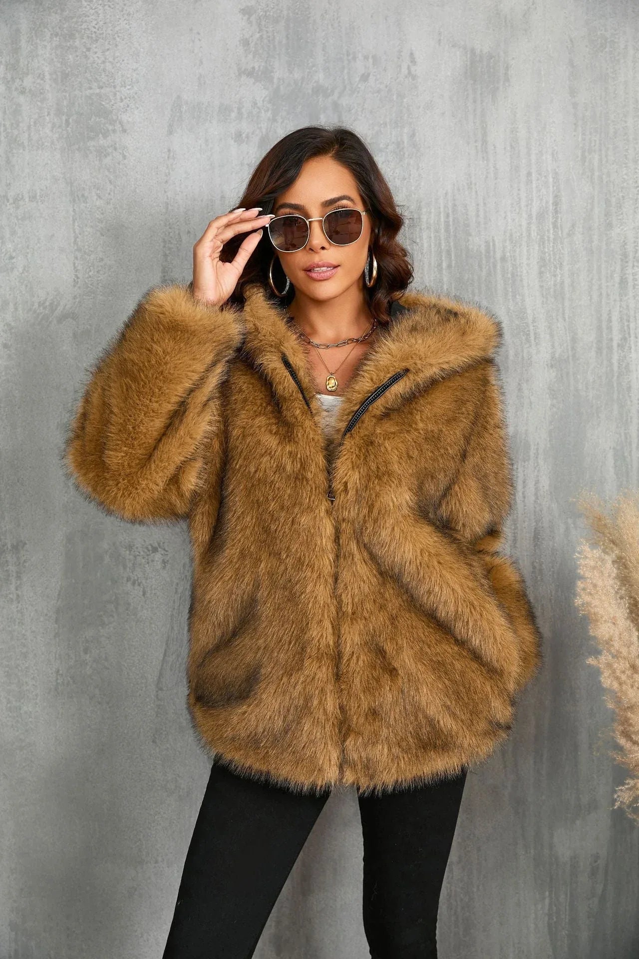 Woman wearing a brown faux fur hooded jacket, adjusting her sunglasses.
