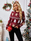 Woman holding a red gift box while wearing a festive red sweater with Christmas designs.
