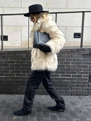 Side view of a woman in a cream faux fur coat, black hat, and black pants walking outdoors.