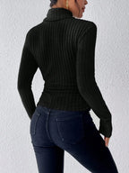 Back view of a woman wearing a black ribbed turtleneck sweater and dark wash jeans.