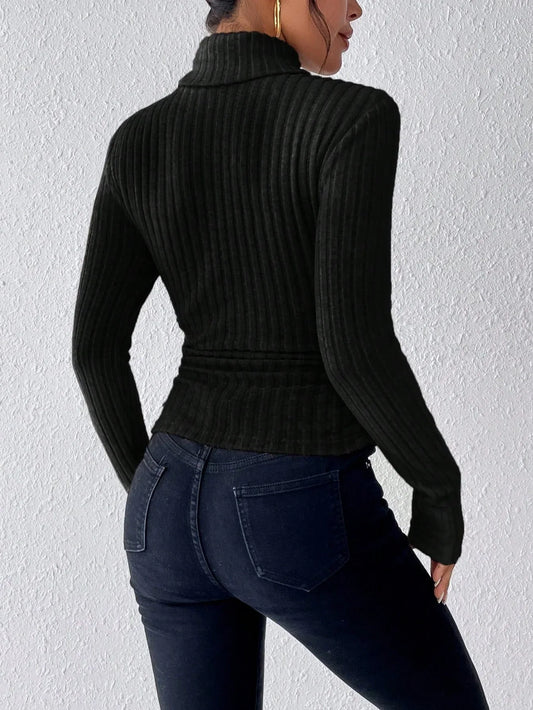 Back view of a woman wearing a black ribbed turtleneck sweater and dark wash jeans.