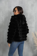 Rear view of a woman wearing a black faux fur hooded jacket and blue jeans.