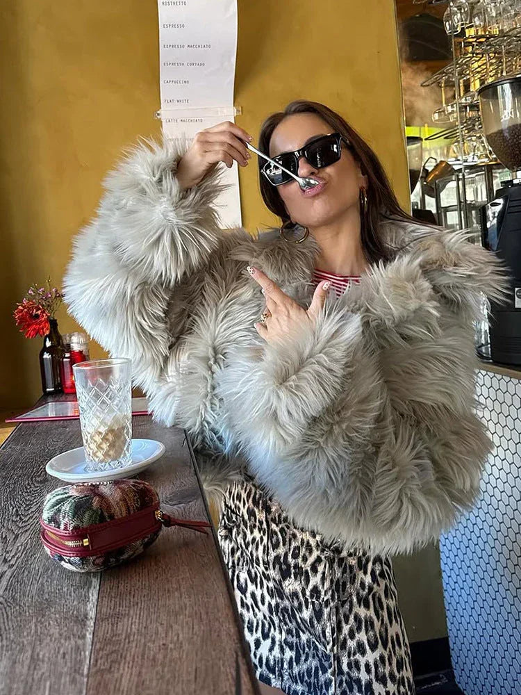 Woman posing in a faux fur jacket and leopard print skirt at a cafe.