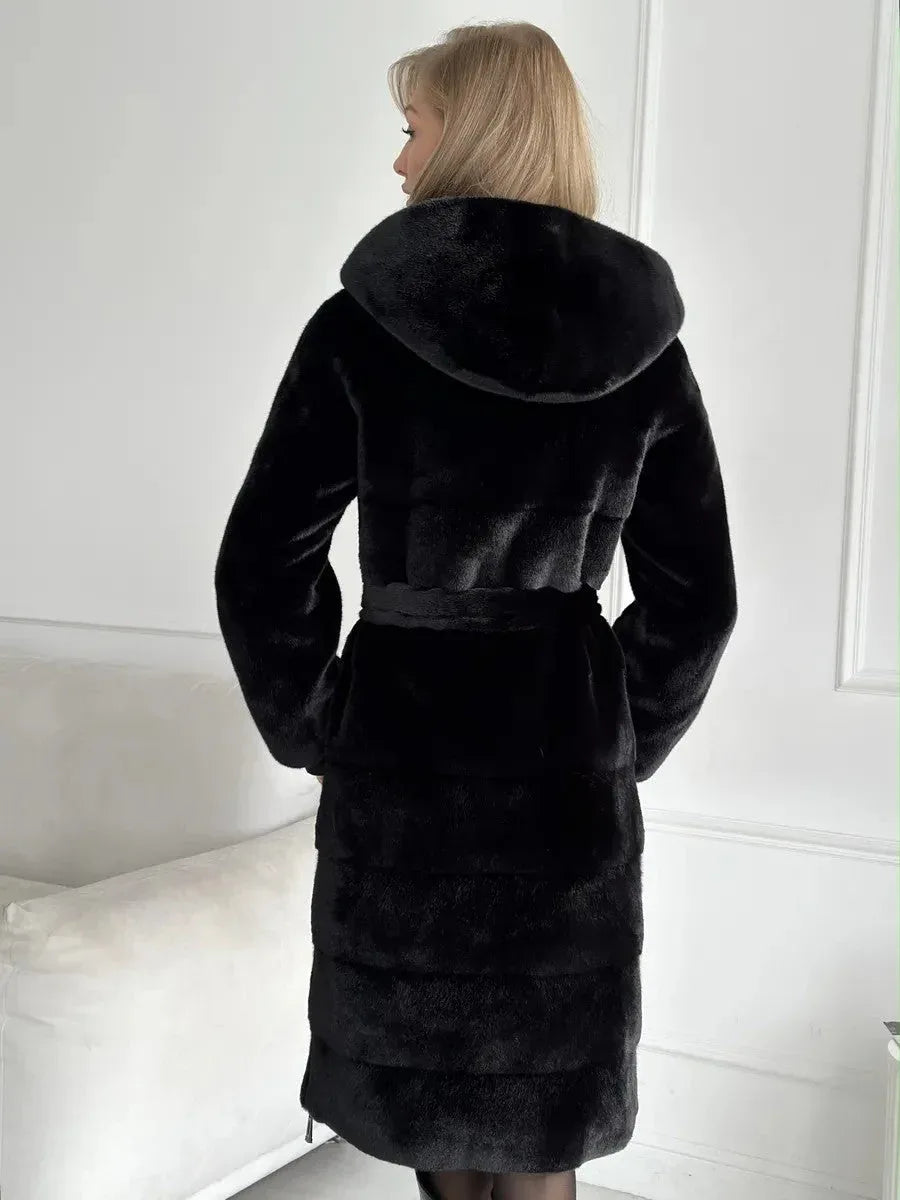 Back view of a woman wearing a black hooded faux fur midi coat with a belted waist.