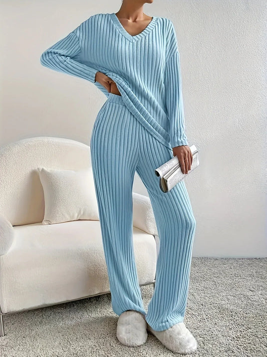 Woman standing with hand on hip in a light blue ribbed loungewear set holding a clutch