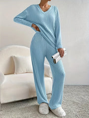 Woman standing with hand on hip in a light blue ribbed loungewear set holding a clutch