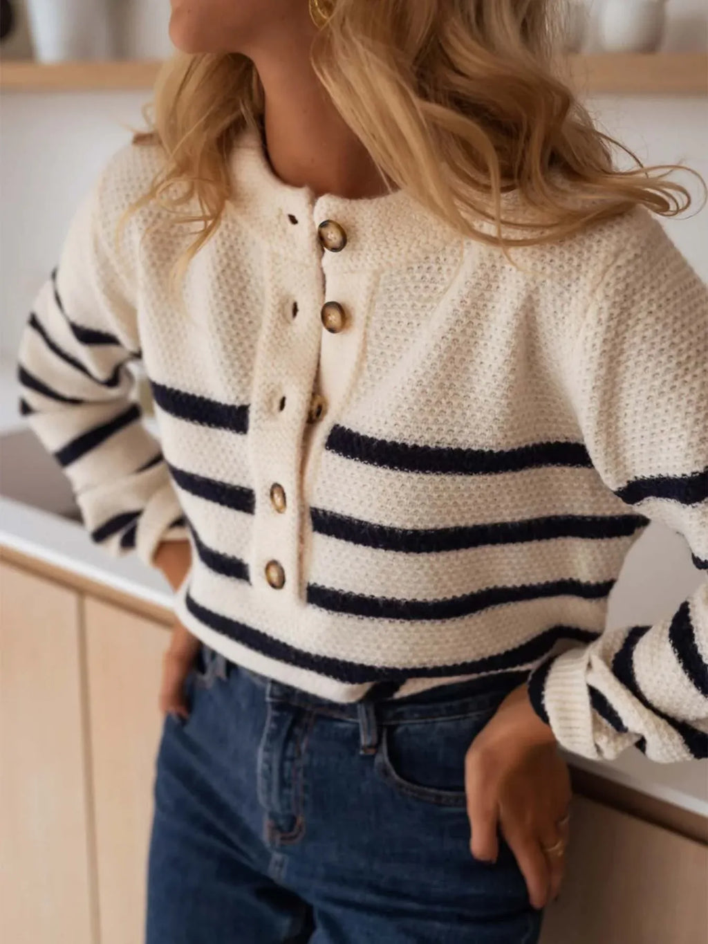 Woman wearing a striped knit sweater and blue jeans, hands on hips