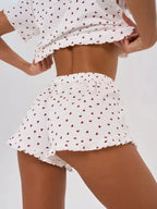 Back view of a woman wearing a white cropped t-shirt and shorts with a red heart print, showing her torso and shorts.