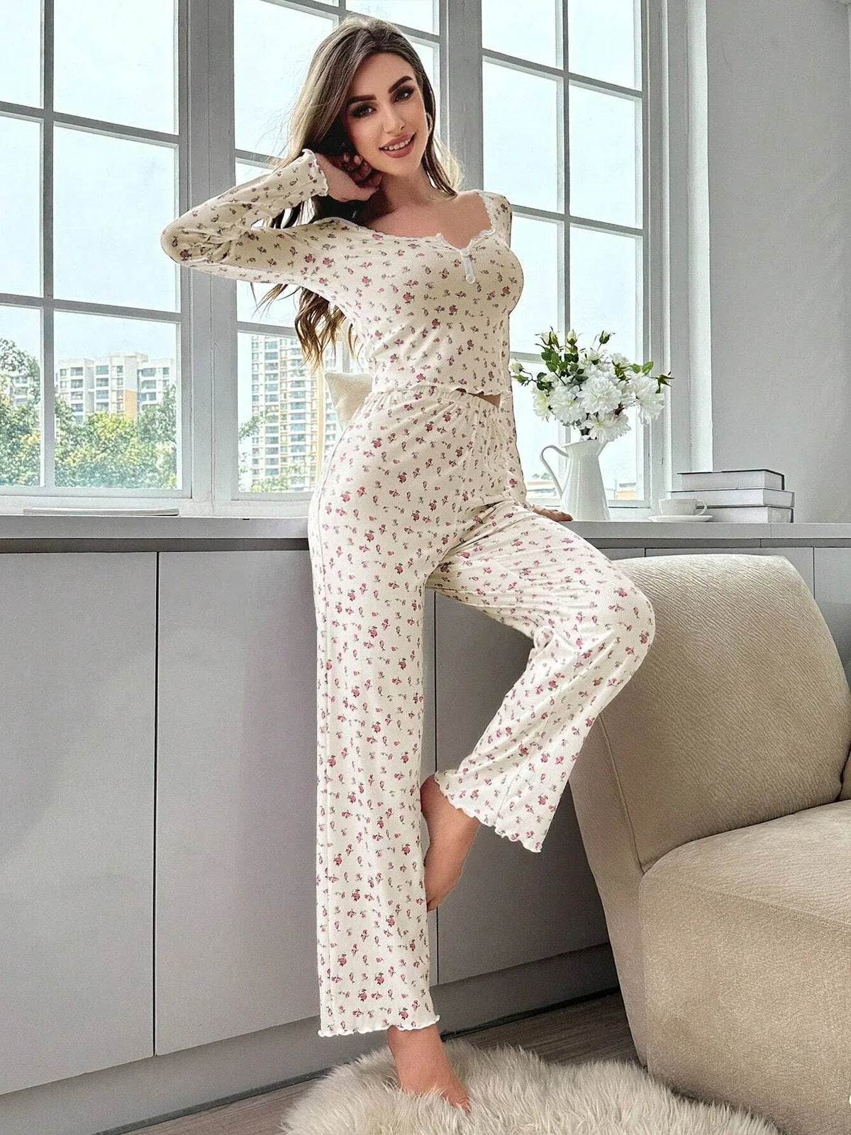 Woman wearing a floral print pajama set standing by a window Main image
