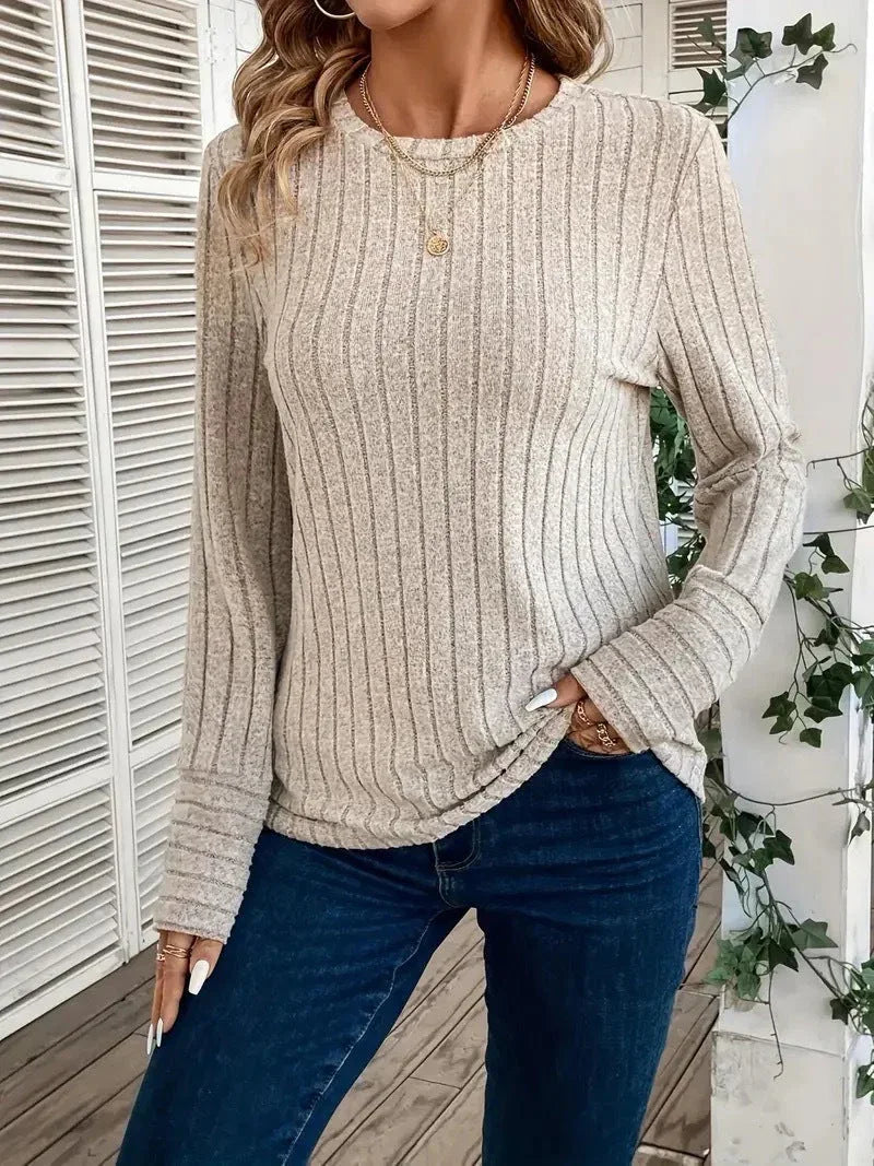 Woman wearing a cream ribbed long-sleeve crew neck top with dark wash jeans