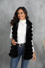 Woman wearing a black faux fur vest over a white turtleneck and blue jeans, looking to the side.