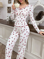 Woman leaning against a dresser wearing white floral print pajamas and holding a teacup