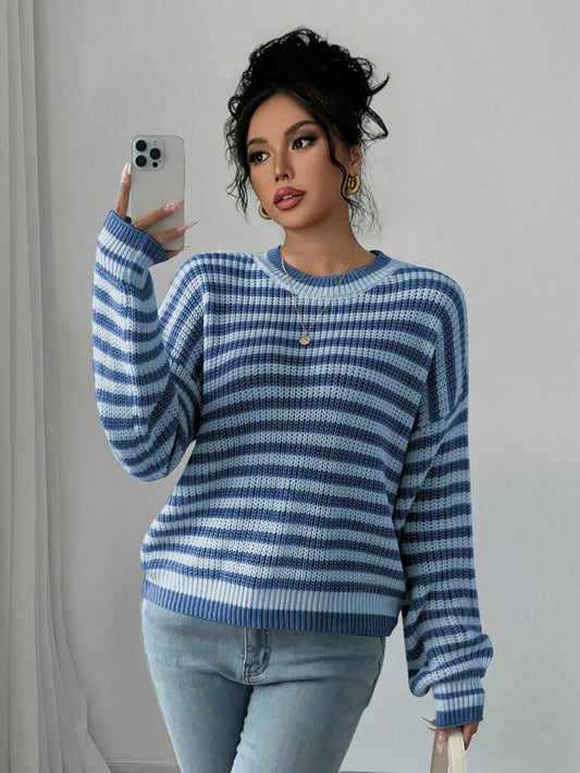 Woman wearing a blue and light blue striped knit sweater and light wash jeans, holding a smartphone to take a selfie.