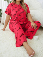Woman wearing a red and black "love" and heart print pajama set sitting on a rug.