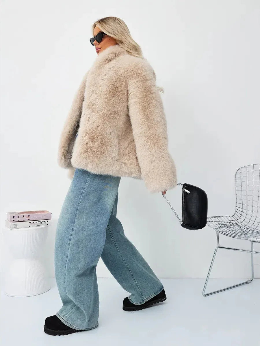 Woman walking wearing a beige faux fur jacket and blue jeans